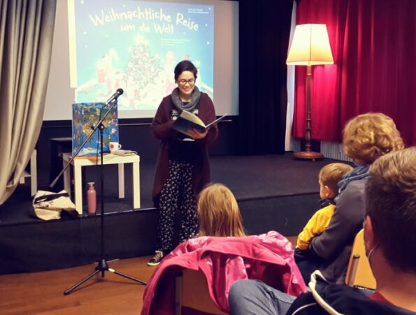 Katharina Mauder steht vor Publikum und liest aus ihrem Adventskalender "Weihnachtliche Reise um die Welt"